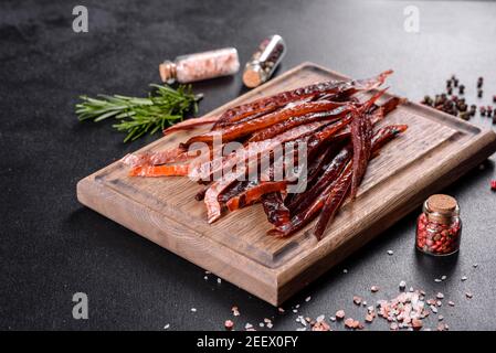 Tasty hearty meat salted and dried with pieces of spices and herbs. Fast and hearty snack Stock Photo
