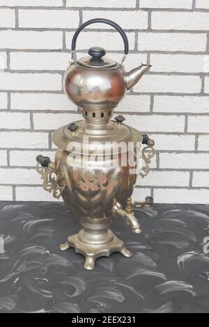 Traditional Russian samovar with kettle for making tea on the wood. Vintage kitchen utensils, close-up. Stock Photo