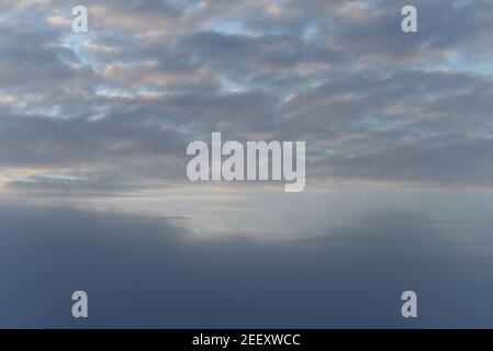 Late autumn sky with clouds, thick fog and the sun partially breaking through the clouds. Stock Photo