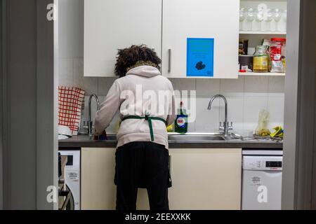 A woman washing up pots and dishes in a kitchen. Fairy Liquid visible next to the sink. Stock Photo