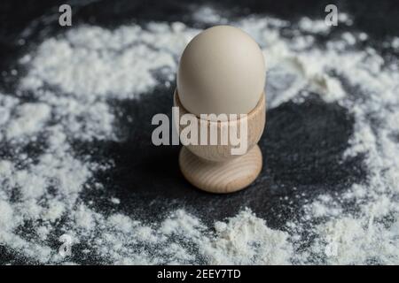 White egg in egg cup on floury background Stock Photo