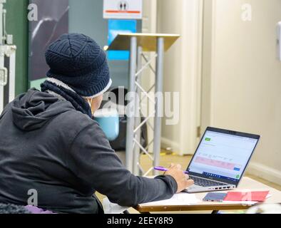 A woman working on a laptop computer enters data into a database. Stock Photo