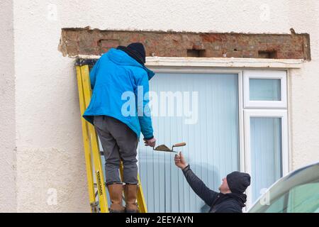 builder working on ladder with trowel and cement, uk Stock Photo