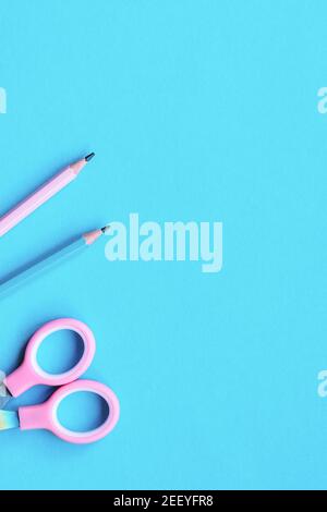 Two wooden pencils and scissors on pink and blue colored paper background. Education concept. Top view, flat lay, copy space. Stock Photo