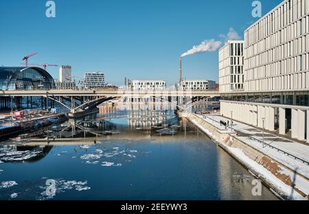 Berlin main railway station Hauptbahnhof, Hbf. Panorama over Spree river with reflection. Snow on riverside, ice on the river. Modern architecture in Stock Photo