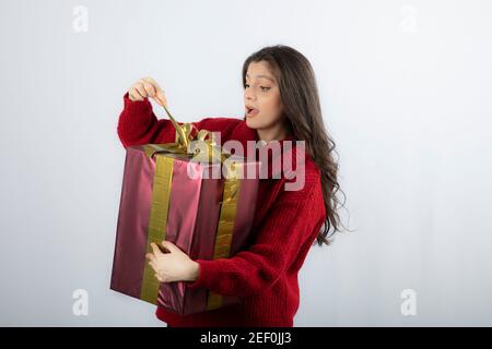 Surprised woman in red sweater opening a box of Christmas present Stock Photo