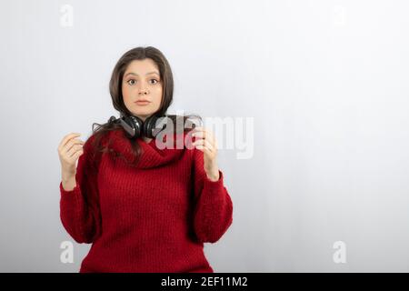 Photo of a young woman in red sweater wearing headphones on neck Stock Photo