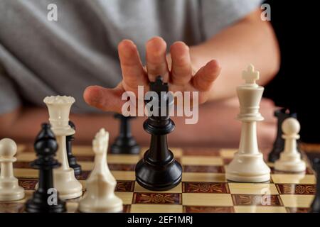 Close up image of the end of a chess came where the losing player resigns by tipping over his king. Image shows as the king falls down. Versatile imag Stock Photo