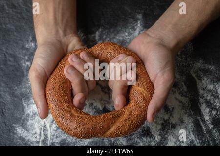 Woman holding fresh Turkish simit on black background Stock Photo