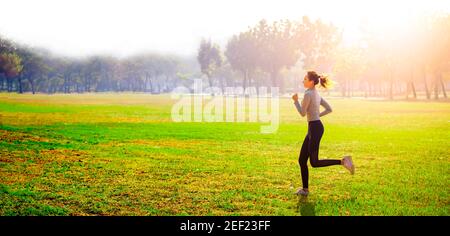 Young beautiful woman running on grass field at morning Stock Photo