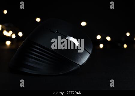 wireless black vertical mouse on black background with lights, latest technology, ergonomic mouse on black background. mouse for designers. mouse for Stock Photo