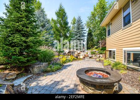 Lush landscaping including a fire pit and pond with waterfall in a luxury North Idaho, USA home. Stock Photo