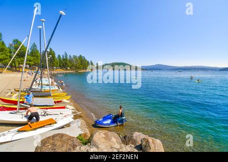 A young man on a wave runner jet ski stands on the beach next to boats at summer in the lakeside town of Coeur d'Alene, Idaho, USA Stock Photo