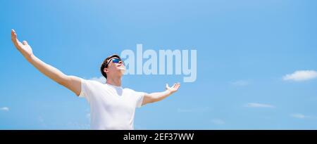 Young man raising his arms, opening palms, looking up in the air empowering himself Stock Photo