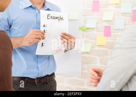 Teacher showing example paper to students while doing group work  in classroom - education concept Stock Photo