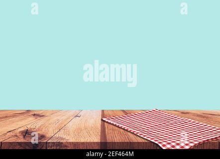 Empty wooden table with red checked tablecloth over blue wall background Stock Photo