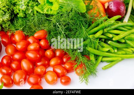 Cherry tomatoes, green peas and dill on white table. Stock Photo