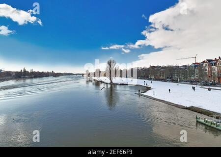 Heidelberg, Germany - February 2021: Neckar river with lower river bank called 'Neckarwiese' with big meadow covered in snow and people taking walks Stock Photo