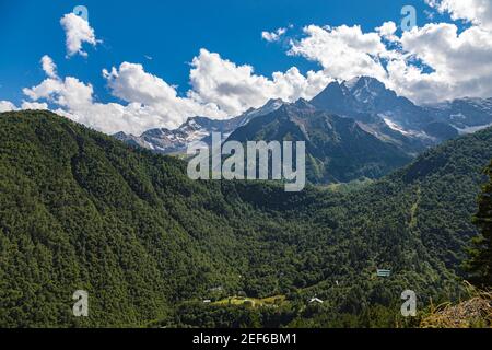 High mountains of the Caucasus with beautiful views. Green vegetation and dense forest above a blue sky. A great fascinating landscape. Stock Photo