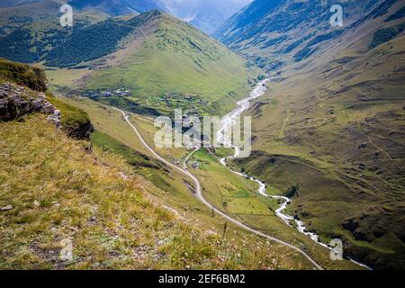 Majestic mountains of the Caucasus with a beautiful view. Green vegetation and shrubs on smooth plains. The river flows along the road. Magnificent me Stock Photo