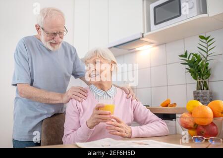 Senior grey-haired man and his wife having a nice morning at home Stock Photo