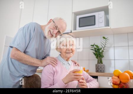 Senior grey-haired man and his wife having a nice morning at home Stock Photo
