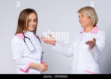 Medical team of two professional doctors talking in meeting. Senior female chief physician helping young female doctor, discussing patient diagnosis Stock Photo