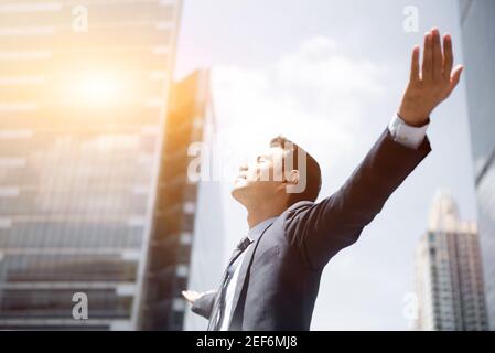 Happy businessman raising his arms, open palms, with face looking up  - empower, success and freedom concepts Stock Photo