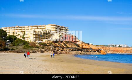 Alicante, Orihuela Costa, Spain - February, 2021: People having a walk on lovely sunny day by the Campoamor beach on weekend  Stock Photo