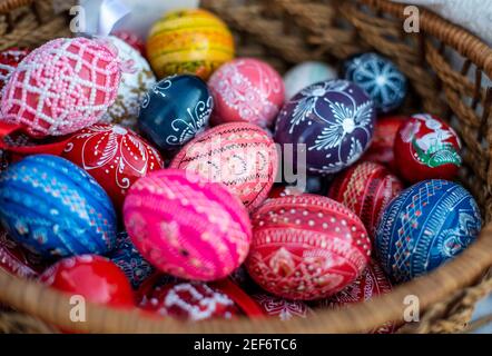 Many colorful decorated easter eggs in wicker basket Stock Photo
