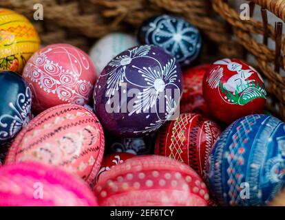 Many colorful decorated easter eggs in wicker basket Stock Photo