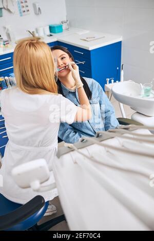 Competent dentist doing teeth cleaning for patient Stock Photo