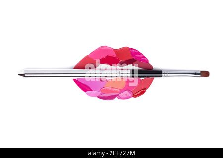 Red and pink lipstick smeared in the shape of lips. Isolated on white background. Cosmetic brushes Stock Photo