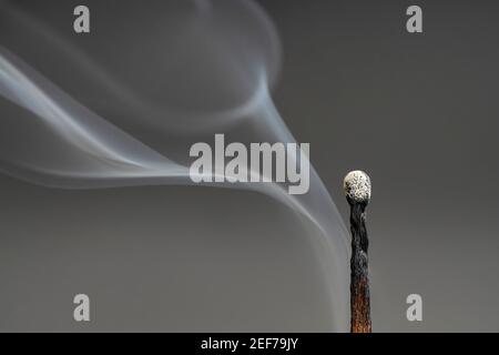 Close-up of the smoke coming from an extinguished match on a grey background Stock Photo