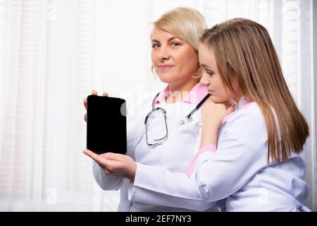 Modern medicine. Doctor showing test results on black mock up digital tablet screen. Two doctors using tablet in meeting at the medical office Stock Photo