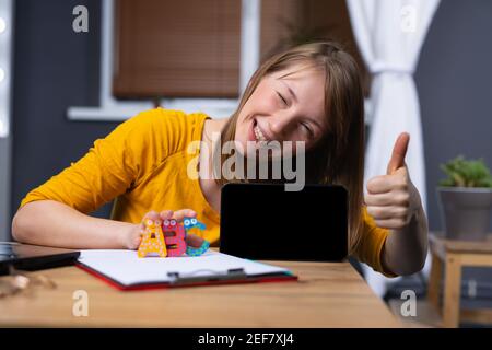 International language online school concept. Smiling woman with like, thumb up showing mock up digital tablet screen on home background. Cool Stock Photo