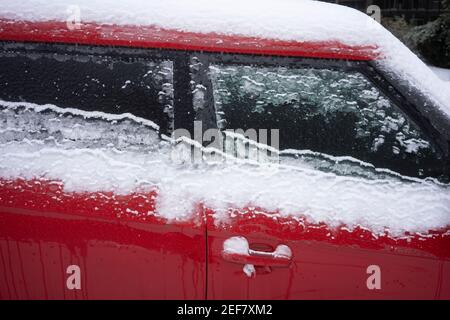 Frozen red car on the streets after snow and freezing rain. Stock Photo