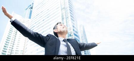 Businessman raising his arms, open palms, with face looking up to the sky - happy, success and achievement concepts, panoramic banner Stock Photo