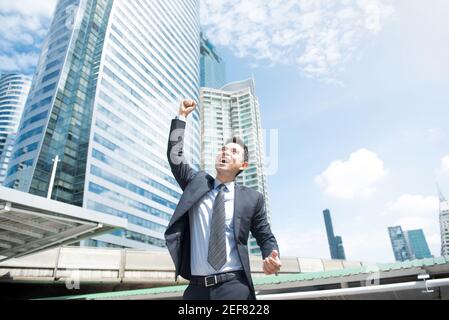 Businessman smiling and raising his fist in the air in office building ...