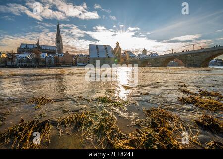 Sunset during flood of Danube river in winter 2021 in Regensburg with view of cathedral the old town and flooded promenade and the stone bridge, Germa Stock Photo