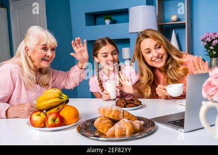 Happy family doing breakfast in the morning at home - Grandmother, daughter and nephew eating at kitchen table at home, domestic life moments Stock Photo