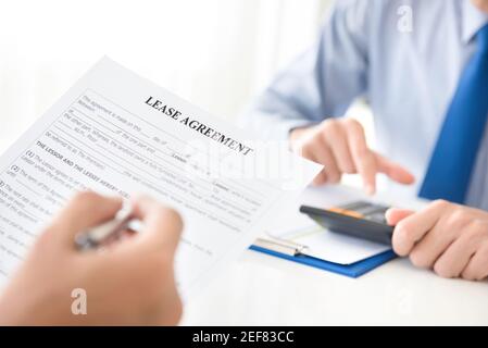 A man reading lease agreement paper, about to fill and sign Stock Photo