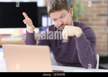 Surprised man looks at laptop screen in office Stock Photo