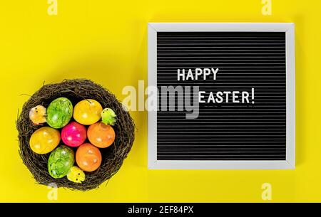 Easter eggs in nest and letter board on the yellow background Stock Photo