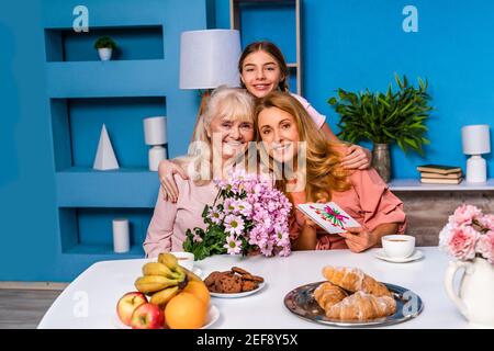 Happy family doing breakfast in the morning at home and celebrating birthtday - Grandmother, daughter and nephew eating at kitchen table at home, dome Stock Photo