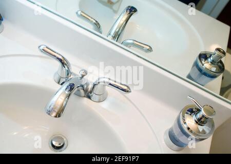 Close-up of a faucet and a soap dispenser on a bathroom sink Stock Photo