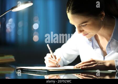 Woman filling paper form late hours in the night at office Stock Photo