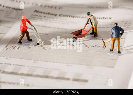 Figurines of manual workers working on a financial newspaper Stock Photo