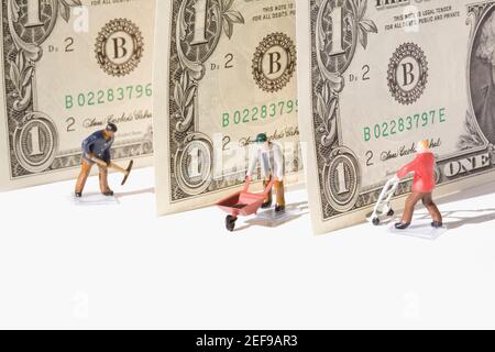 Figurines of manual workers with US dollar bills Stock Photo