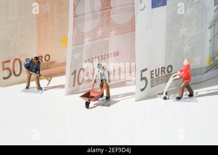 Figurines of manual workers with European union banknotes Stock Photo